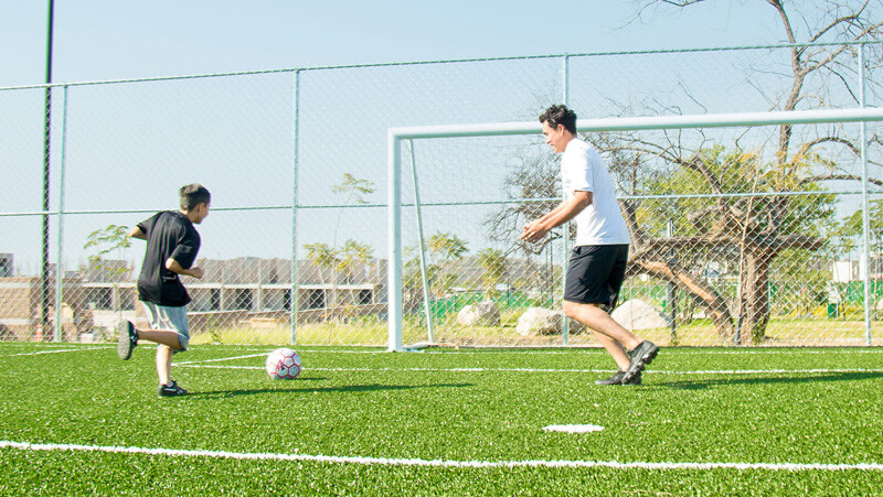 Padre e hijo juegan juntos en la cancha deportiva de una amenidad dentro del desarrollo Santa Fe Ubicado en Xochitepec, Morelos
